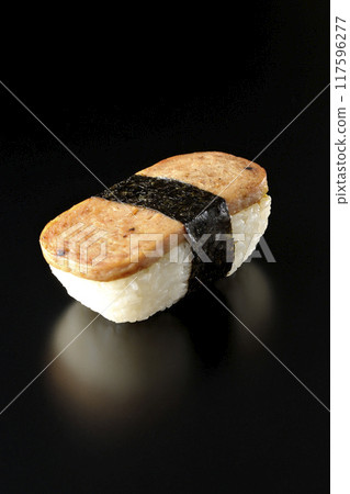 Spam musubi photographed against a black background 117596277
