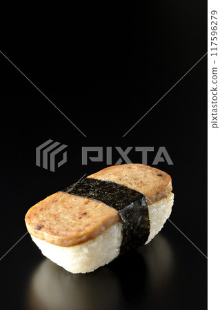 Spam musubi photographed against a black background 117596279