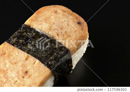 Spam musubi photographed against a black background 117596301