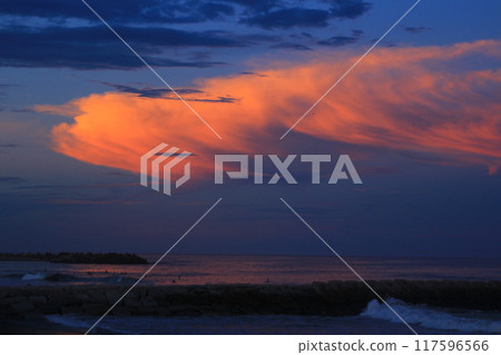 Sunset clouds and surfers on the ocean 117596566