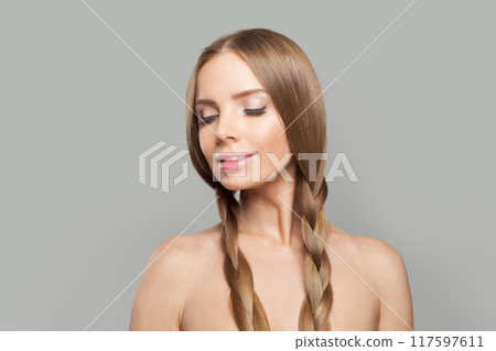 Smiling female model brunette with long hair and natural make-up posing isolated on white background Smiling female model brunette with long hair and natural make-up posing isolated on white background 117597611