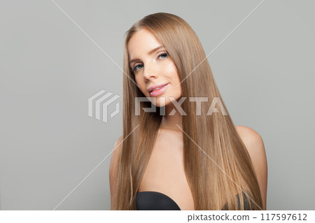 Stylish woman face. Model with long brown hair and make-up on grey background.  117597612