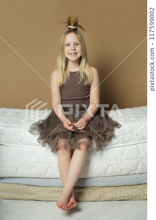Happy girl sitting on mattress at home Happy girl sitting on mattress at home 117599002