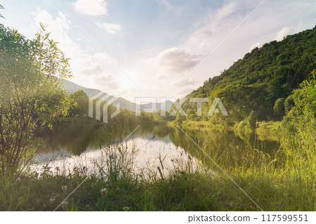 Beautiful summer morning landscape. Clear water mountains lake, blue cloudy sky, sun rays. Beautiful summer morning landscape. Clear water mountains lake, blue cloudy sky, sun rays. 117599551