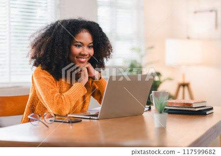 African American woman smiles while watching laptop screen at home. African American woman smiles while watching laptop screen at home. 117599682