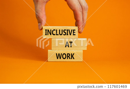 Inclusive at work symbol. Wooden blocks with words 'Inclusive at work' on beautiful orange background. Businessman hand. Business, inclusive at work concept. Copy space. 117601469