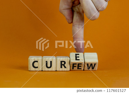 Curfew and cure symbol. Businessman turns cubes and changes the word 'curfew' to 'cure'. Beautiful orange background. Business, curfew and cure concept. Copy space. 117601527