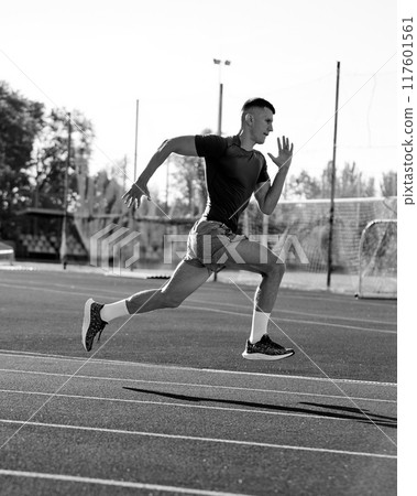 Black and white filter. Dynamic photo of young athletic man picks up speed before finish line to come first in competition and win. 117601561