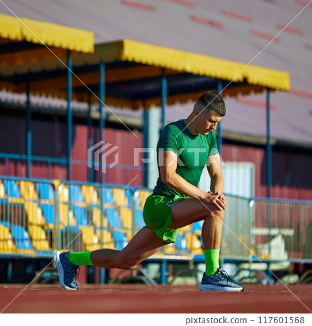 Young athletic man stretching legs before marathon on field outdoor. Training session on start line. Young athletic man stretching legs before marathon on field outdoor. Training session on start line. 117601568