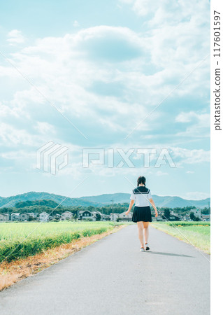 夏天,穿著水手服、綁著辮子的女孩沿著稻田小路行走 夏天,穿著水手服、綁著辮子的女孩沿著稻田小路行走 117601597