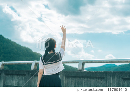 一個穿著水手服的女孩在橋上伸向藍天的後視圖 一個穿著水手服的女孩在橋上伸向藍天的後視圖 117601640