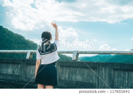 一個穿著水手服的女孩在橋上伸向藍天的後視圖 117601641