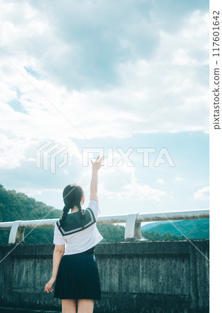 一個穿著水手服的女孩在橋上伸向藍天的後視圖 一個穿著水手服的女孩在橋上伸向藍天的後視圖 117601642