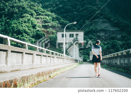 一個穿著水手服的女孩在橋上的路上行走的後視圖 一個穿著水手服的女孩在橋上的路上行走的後視圖 117602200
