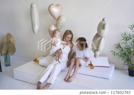 a photo session on the first birthday of a baby girl with her mother and teenage sister, in pastel colors, minimalism a photo session on the first birthday of a baby girl with her mother and teenage sister, in pastel colors, minimalism 117602765