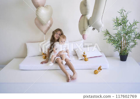 a        photo session on the first birthday of a baby girl with her  teenage sister, in pastel colors, minimalism 117602769