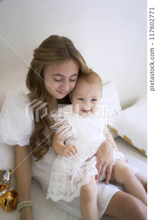 a        photo session on the first birthday of a baby girl with her  teenage sister, in pastel colors, minimalism 117602771