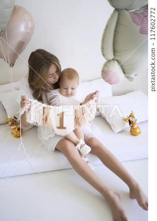 a        photo session on the first birthday of a baby girl with her  teenage sister, in pastel colors, minimalism 117602772