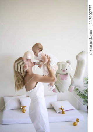 mother with a baby girl in a stylish white minimalist interior in white clothes mother with a baby girl in a stylish white minimalist interior in white clothes 117602775