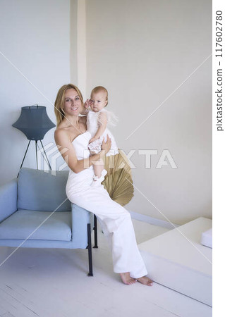 mother with a baby girl in a stylish white minimalist interior in white clothes mother with a baby girl in a stylish white minimalist interior in white clothes 117602780