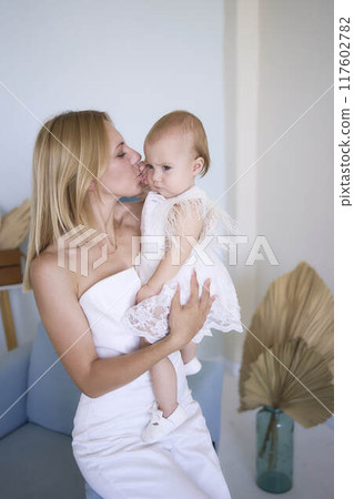 mother with a baby girl in a stylish white minimalist interior in white clothes mother with a baby girl in a stylish white minimalist interior in white clothes 117602782