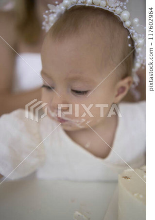 baby girl tries her first birthday cake with mom and pre-teen sister 117602964