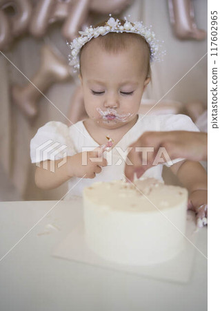 baby girl tries her first birthday cake with mom and pre-teen sister 117602965