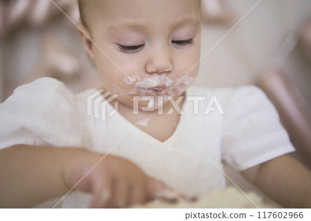 baby girl tries her first birthday cake with mom and pre-teen sister 117602966