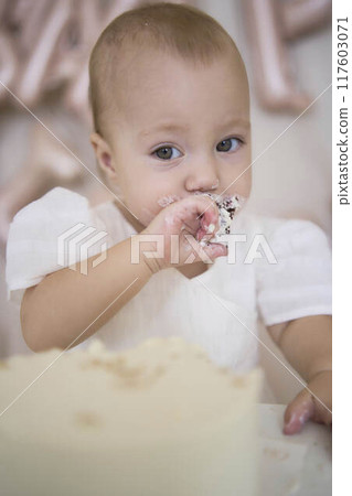 baby girl tries her first birthday cake with mom and pre-teen sister 117603071