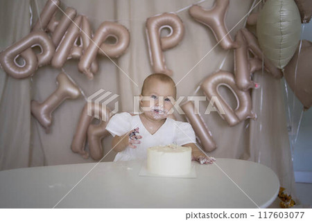 baby girl tries her first birthday cake with mom and pre-teen sister 117603077
