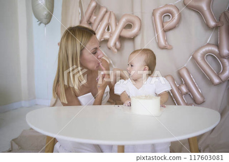 baby girl tries her first birthday cake with mom and pre-teen sister baby girl tries her first birthday cake with mom and pre-teen sister 117603081