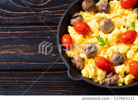 Healthy vegetarian breakfast . Scrambled eggs in pan with cherry tomatoes and parsley 117603111