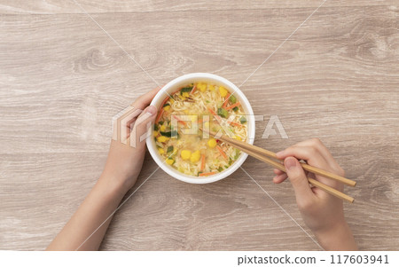 一個女孩吃杯拉麵。 117603941