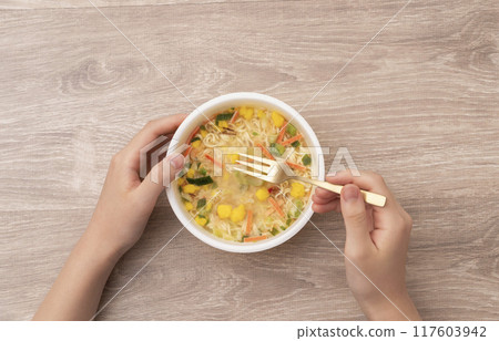 一個女孩吃杯拉麵。 117603942