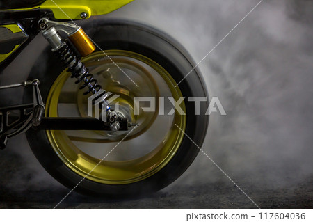 Motorbike burning tire rubber with white smoke for race, Motorbike burning tire rubber, Motorbike burns wheel on race track. 117604036