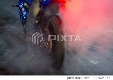 Motorbike burning tire rubber with white smoke for race, Motorbike burning tire rubber, Motorbike burns wheel on race track. 117604037
