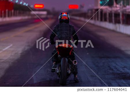 Motorcylce rider protective cloth with motorcycle ready to race, Motorcycle on the asphalt race track. Motorcylce rider protective cloth with motorcycle ready to race, Motorcycle on the asphalt race track. 117604041