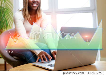 A woman is sitting in front of a laptop with a graph on the screen A woman is sitting in front of a laptop with a graph on the screen 117605753