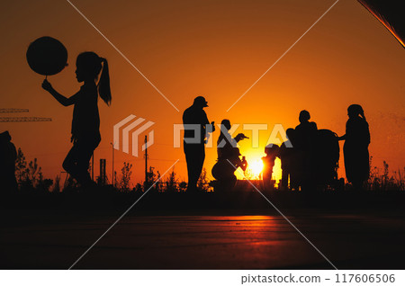 Silhouettes of people from different generations having fun in a public park at sunset - a concept of community and support Silhouettes of people from different generations having fun in a public park at sunset - a concept of community and support 117606506