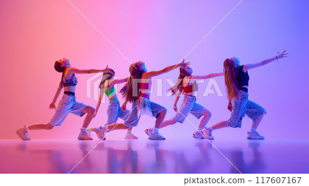 Group of talented young girls dancing in motion in neon light against gradient pink background. Dance school. Group of talented young girls dancing in motion in neon light against gradient pink background. Dance school. 117607167