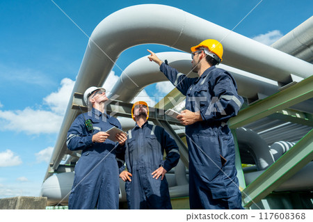 Three of engineer or factory technician worker team stand under petrochemical gas pipeline with one also point to the pipeline in workplace. 117608368