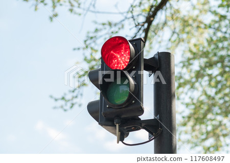 Close-up of red traffic light for cars with a blue sky in the background. Close-up of red traffic light for cars with a blue sky in the background. 117608497