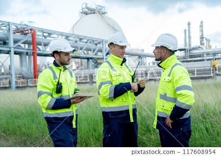 Group of engineer or technician workers stand on the road near petrochemical factory and discuss their work. 117608954