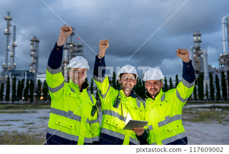 Group of engineer or technician workers stand in front petrochemical factory and raise their hands up to express happiness. Group of engineer or technician workers stand in front petrochemical factory and raise their hands up to express happiness. 117609002