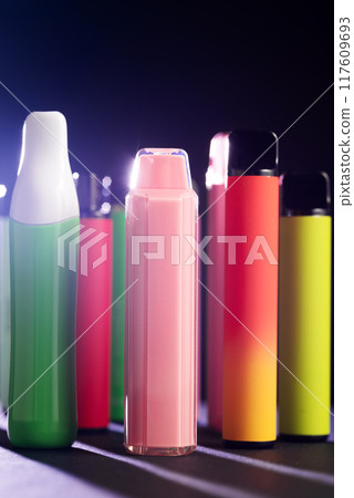A set of colorful disposable electronic cigarettes of different shapes on a black background with smoke. Concept of modern smoking, vaping and nicotine. A set of colorful disposable electronic cigarettes of different shapes on a black background with smoke. Concept of modern smoking, vaping and nicotine. 117609693