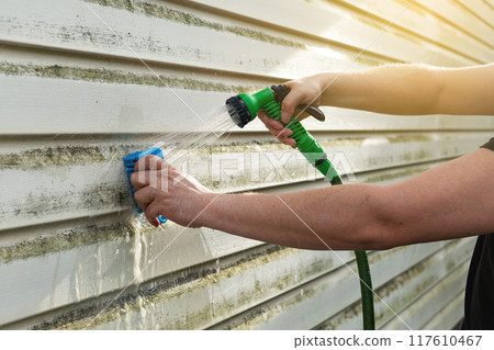 Cleaning algae and mold from vinyl siding of house with pressure spray jet Cleaning algae and mold from vinyl siding of house with pressure spray jet 117610467