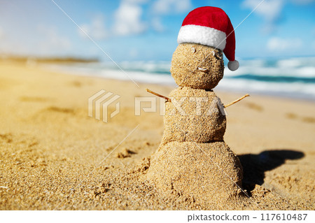 Caribbean Christmas Snowman with Santa Claus Hat made out of sand on sandy beach. Holiday vacation. New Year travel greeting card 117610487