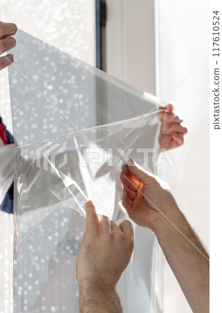 Installation of tinted film. Ultraviolet and energy afficiency concept. Installation of tinted film. Ultraviolet and energy afficiency concept. 117610524