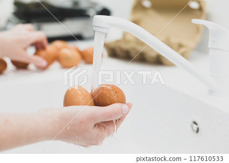 Washing chicken eggs under water Washing chicken eggs under water 117610533