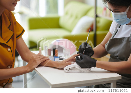 Receiving Manicure in Cozy Salon Setting With Bright Light 117611051